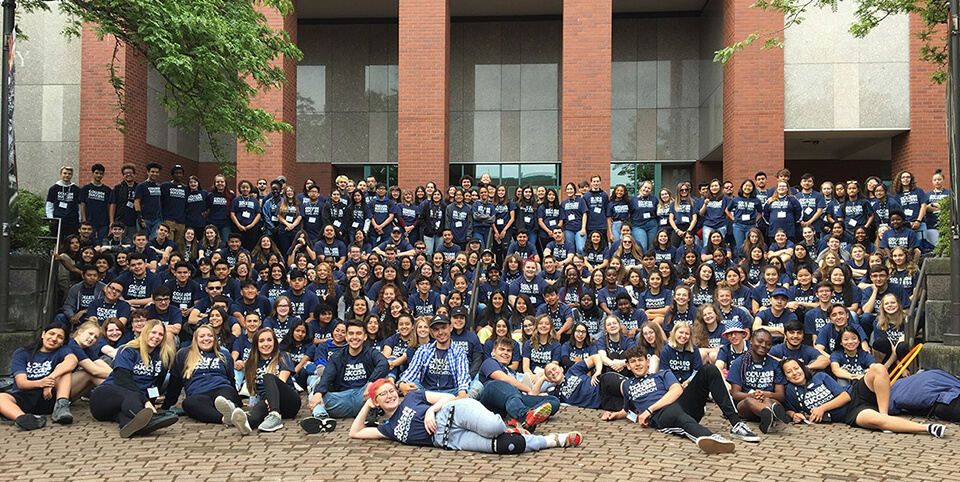 A large group of CSF Spokane Scholars poses in front of a large academic building in College Success Foundation shirts.