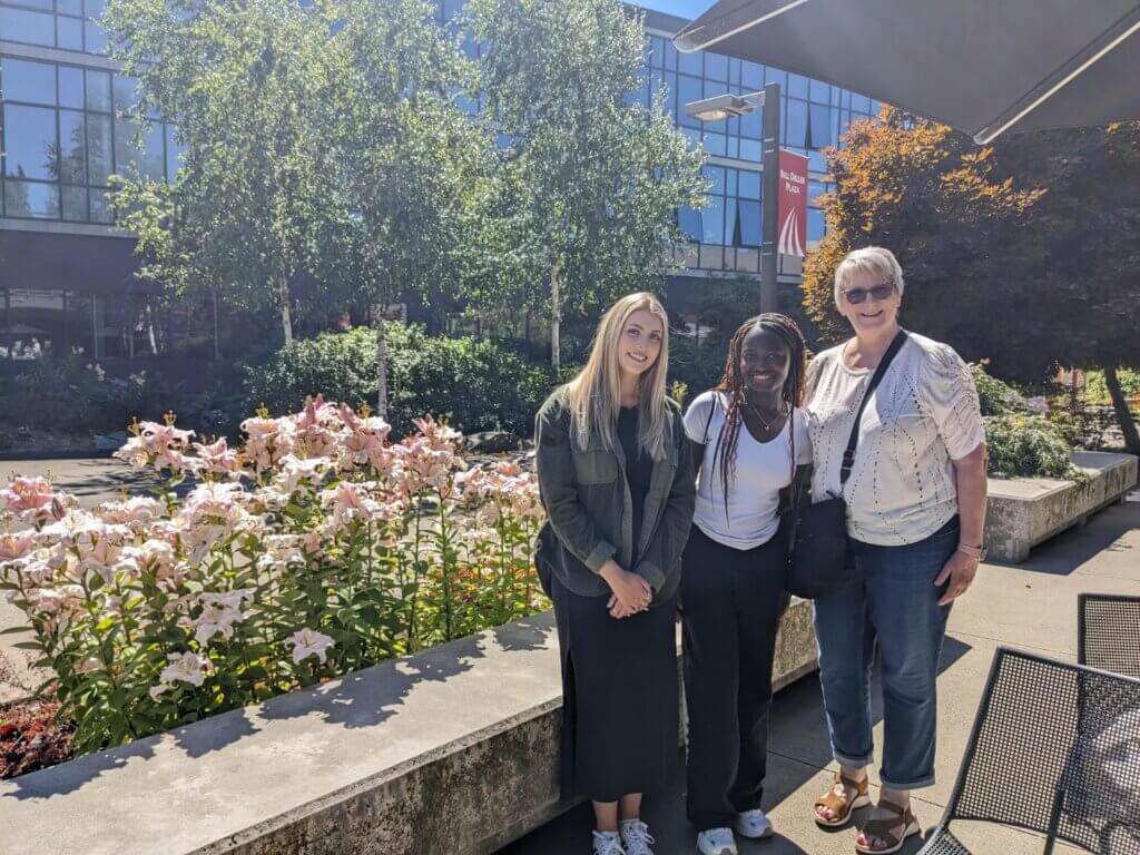 CSF Scholar JJ poses with her advisor and college coach in a garden on her college campus.